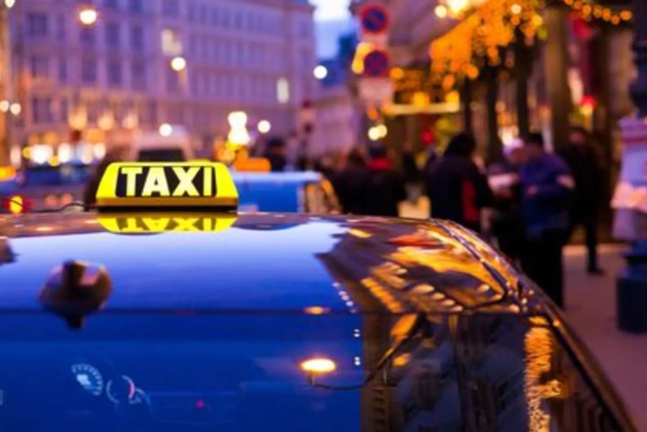 Leuchtendes Taxischild auf einem Auto am Abend in der Stadt